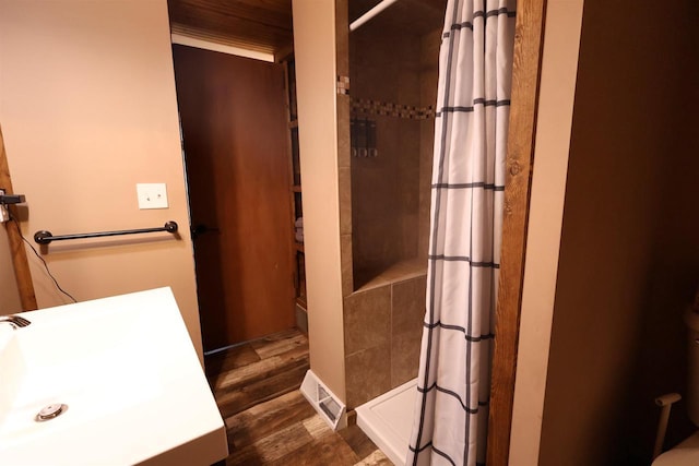 bathroom featuring a sink, wood finished floors, and a stall shower