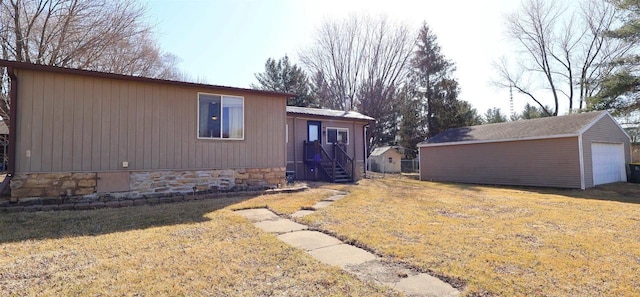 view of front of property with an outdoor structure, a front yard, and a detached garage