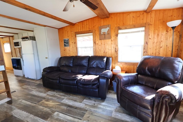 living room featuring beam ceiling, wooden walls, ceiling fan, and wood finished floors