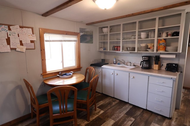 kitchen with beam ceiling, open shelves, dark wood-style flooring, a sink, and light countertops