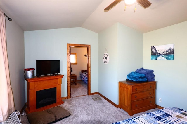 carpeted bedroom featuring baseboards, lofted ceiling, ceiling fan, and a fireplace