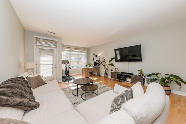 living room featuring visible vents, baseboards, and wood finished floors