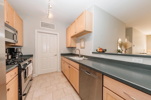 kitchen with visible vents, a sink, light brown cabinetry, stainless steel appliances, and dark countertops