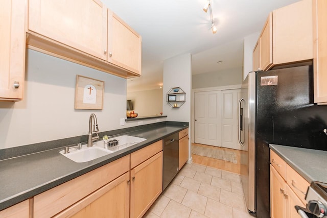 kitchen featuring light brown cabinetry, appliances with stainless steel finishes, dark countertops, and a sink