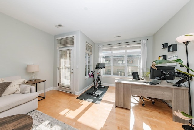 office space with baseboards, visible vents, and light wood-type flooring