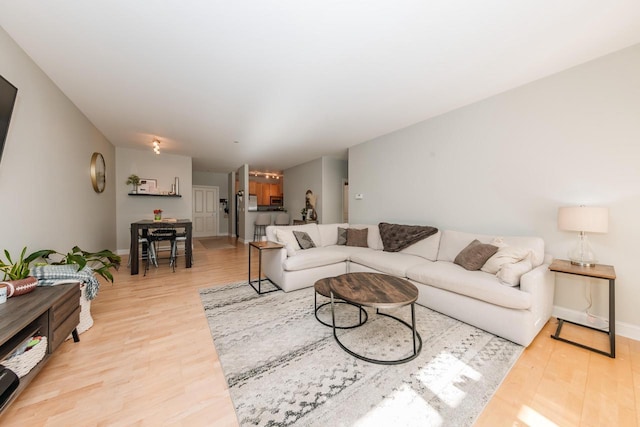 living area with baseboards and light wood finished floors