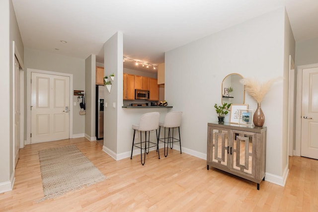 kitchen featuring a kitchen breakfast bar, baseboards, light wood-type flooring, and stainless steel appliances