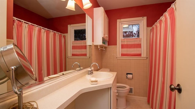 bathroom with vanity, visible vents, wainscoting, tile walls, and toilet