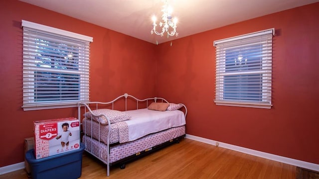 bedroom with a notable chandelier, baseboards, and wood finished floors