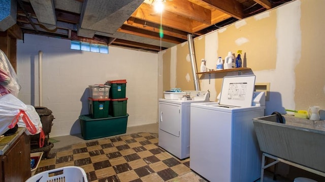 laundry area with concrete block wall, washing machine and clothes dryer, laundry area, a sink, and tile patterned floors