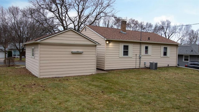 back of property with central AC, a chimney, and a yard