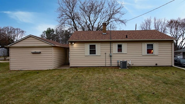 back of property featuring a shingled roof, cooling unit, a lawn, and a chimney