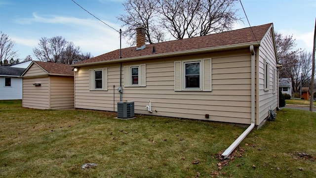 back of house featuring central air condition unit, a lawn, and a chimney