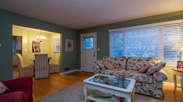 living area featuring baseboards, plenty of natural light, a notable chandelier, and wood finished floors