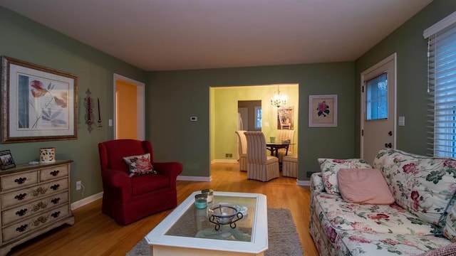 living room with an inviting chandelier, light wood-style flooring, and baseboards