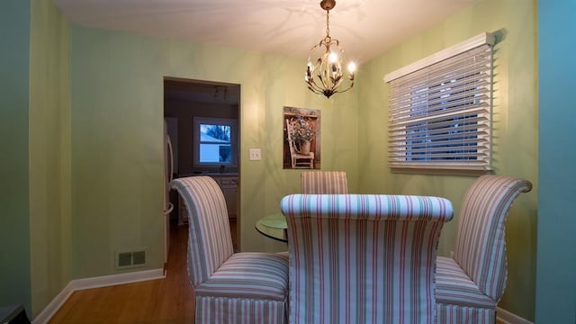 dining room with an inviting chandelier, wood finished floors, visible vents, and baseboards