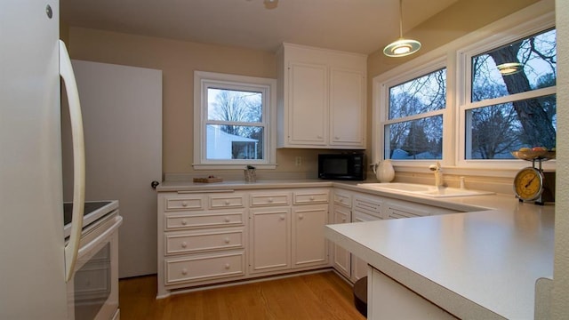 kitchen with black microwave, light countertops, stainless steel electric range, freestanding refrigerator, and a sink