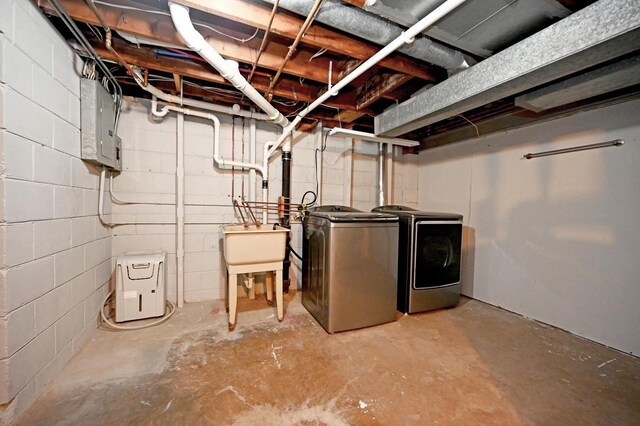 unfinished basement with electric panel, a sink, and separate washer and dryer