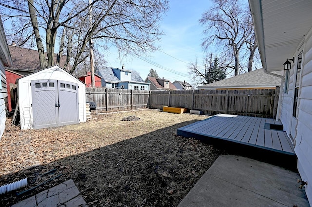 view of yard featuring a fenced backyard, a deck, a storage shed, and an outdoor structure