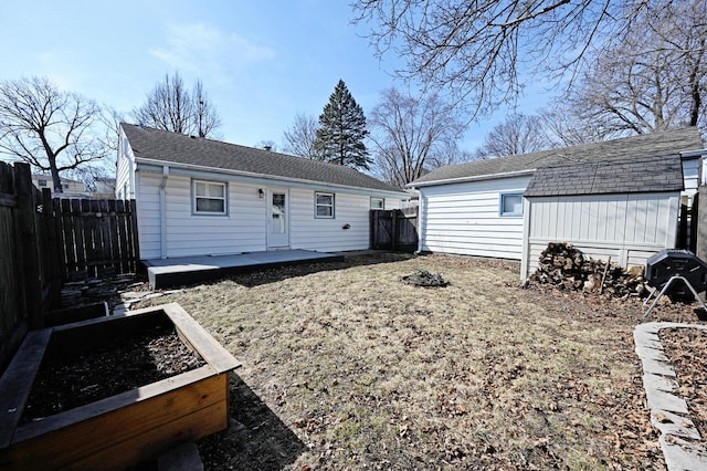 rear view of property with an outdoor structure, a vegetable garden, and a fenced backyard