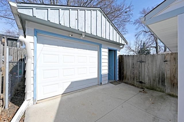 detached garage featuring fence and driveway