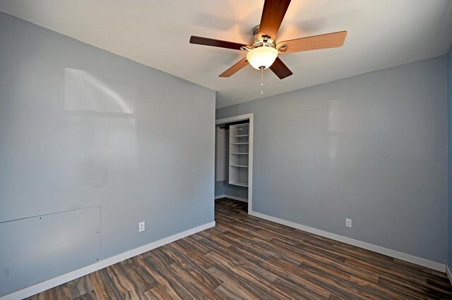 empty room featuring dark wood-type flooring, a ceiling fan, and baseboards