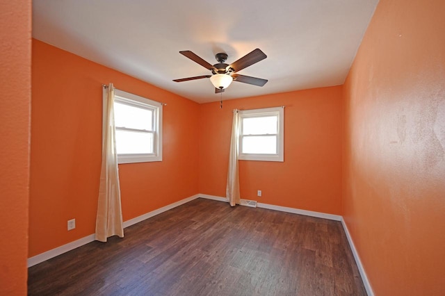 unfurnished room with dark wood-style floors, plenty of natural light, and baseboards