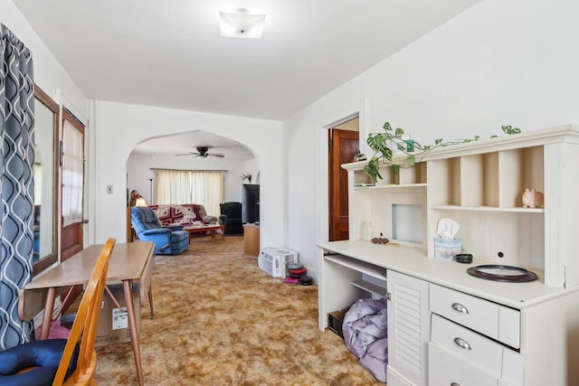 interior space featuring arched walkways, light colored carpet, and a ceiling fan