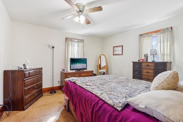 bedroom featuring baseboards, multiple windows, light colored carpet, and ceiling fan