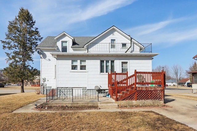 back of property with a balcony and a shingled roof