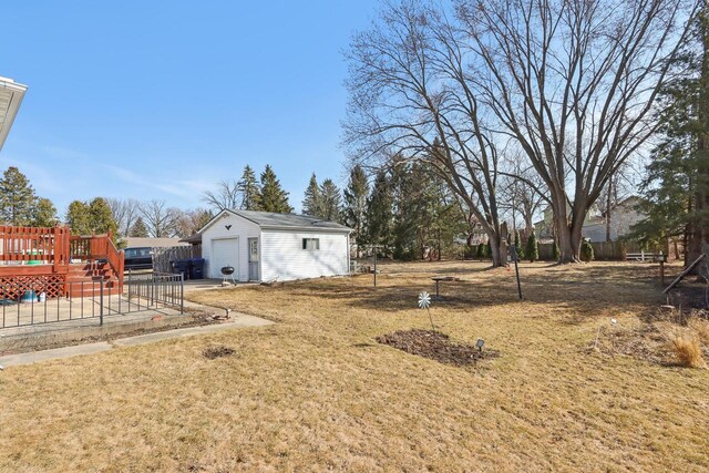 view of yard featuring an outdoor structure, fence, a detached garage, and a wooden deck