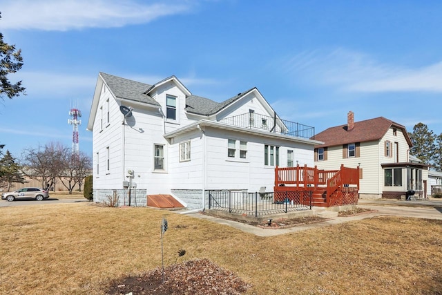 back of house with a yard, a balcony, and a shingled roof