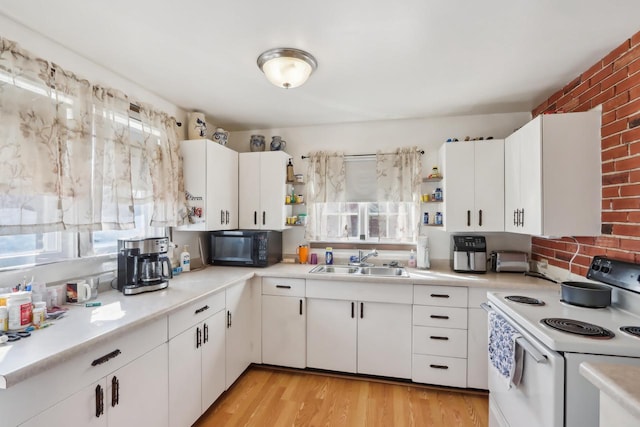 kitchen featuring electric range, light wood-style flooring, a sink, light countertops, and black microwave