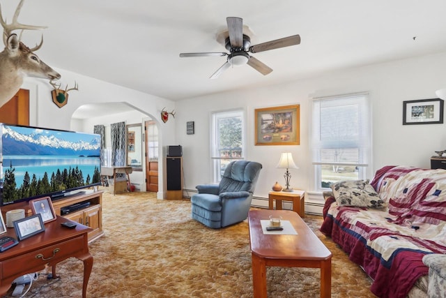 living room featuring arched walkways, carpet flooring, baseboard heating, and a ceiling fan