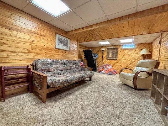 carpeted living area featuring wooden walls and a paneled ceiling