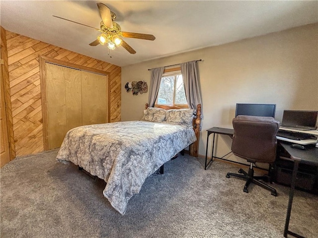 carpeted bedroom featuring a closet, wooden walls, and ceiling fan