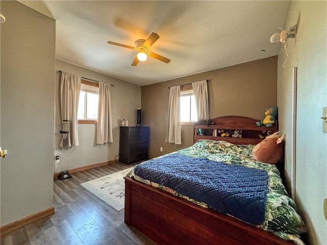 bedroom with baseboards, multiple windows, and wood finished floors