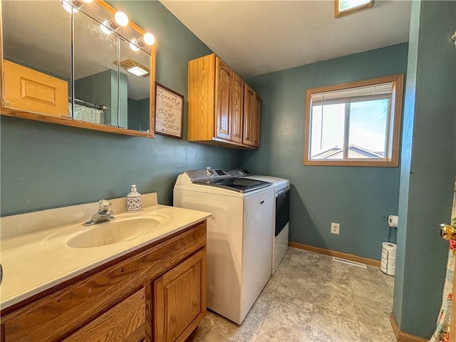 clothes washing area with washing machine and clothes dryer, laundry area, baseboards, and a sink