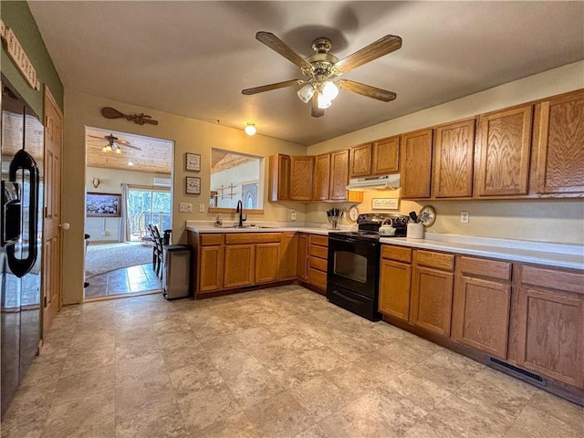 kitchen with under cabinet range hood, light countertops, brown cabinets, black electric range oven, and a ceiling fan