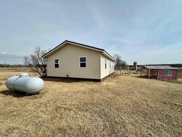 view of side of property with a yard, an outbuilding, and fence