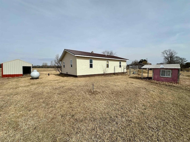 rear view of property with an outbuilding and a lawn