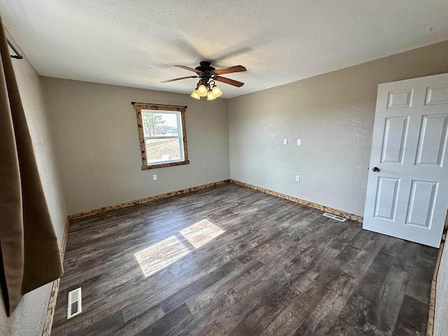 unfurnished room with visible vents, a textured ceiling, baseboards, ceiling fan, and dark wood-style flooring