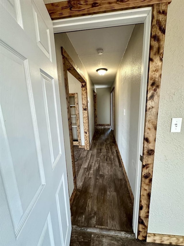 corridor with wood finished floors and a textured wall