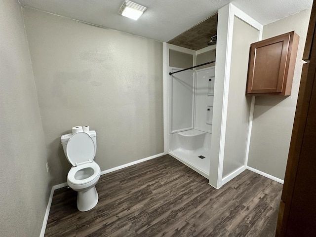 full bath featuring baseboards, wood finished floors, toilet, and a stall shower