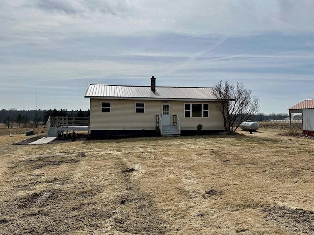 rear view of property with metal roof and a chimney