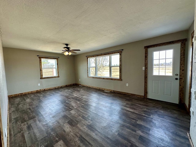 interior space with dark wood finished floors, a textured ceiling, baseboards, and ceiling fan