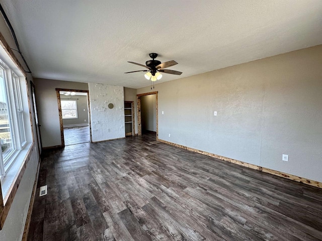 spare room with visible vents, baseboards, dark wood-style floors, a textured ceiling, and a ceiling fan