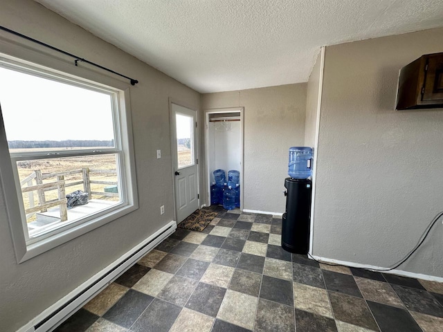 interior space with a baseboard heating unit, baseboards, and a textured wall