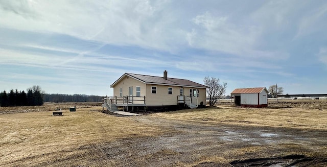 view of property exterior with an outbuilding, a storage unit, and a chimney