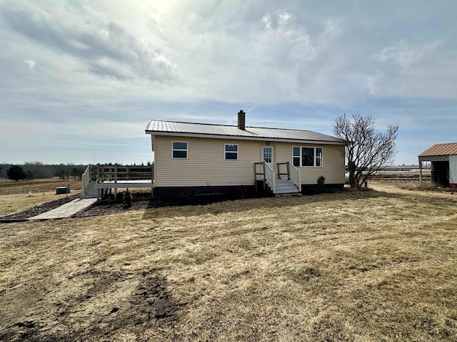 rear view of property featuring metal roof and a chimney